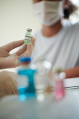Fototapeta premium Close-up of doctor holding bottle with medicine and suggesting the vaccination to patient