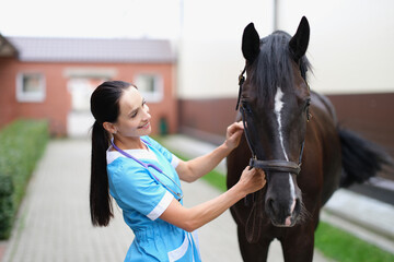 Woman veterinarian holding reins of horse at farm