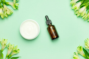 Skin care products, natural cosmetic. Flat lay image on green background Natural cosmetic skincare bottle, serum and flowers. Homemade and beauty product concept.