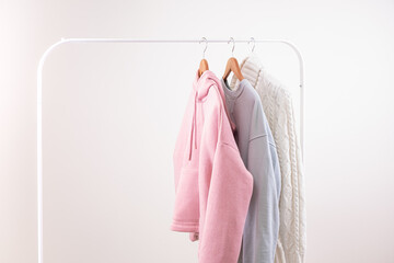 Pastel colors casual female clothes on wooden hangers on open rail copy space