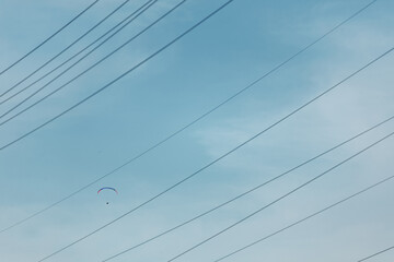 Skydiver flies in the sky against the background of wires