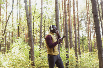 African american man listens music in spring park copy space and place for advertising. Gadget, app and streaming service concept