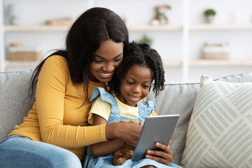 Technologies For Leisure. Happy Black Mother And Little Daughter Using Digital Tablet