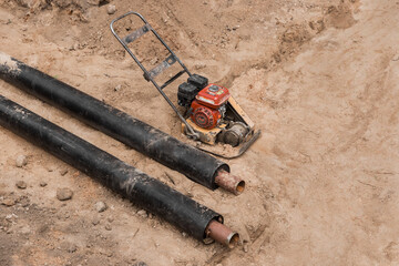 Repair of the water line of the heating main pipe in the ground trench pipeline at the construction site work industry, soil compaction pneumatic rammer