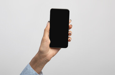 Businesswoman hand showing smartphone with empty black screen, demonstrating space for app or website design
