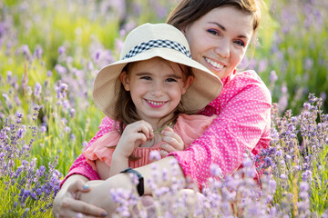 Mother and her daughter at lavender field full of blooming flowers.