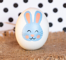 Easter egg with a bunny pattern next to a gift bag. easter bunny painted on a white egg