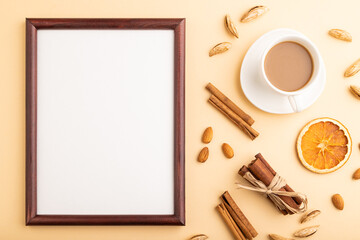 Obraz na płótnie Canvas Composition with wooden frame, almonds, cinnamon and cup of coffee. mockup on orange background. top view, copy space.