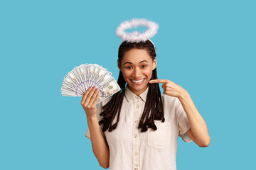 Portrait of smiling angelic woman with dreadlocks and nimb over head holding and pointing at fan of...
