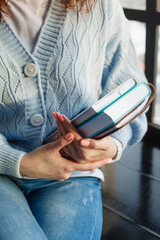 A girl in a blue knitted sweater holds books and a notebook in her hands	
