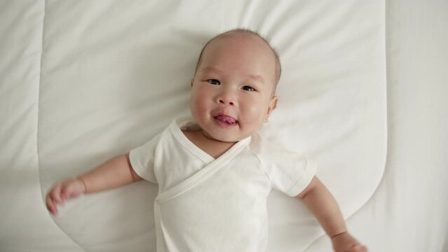 Portrait Asian newborn baby in white cloth on bed happy and funny
