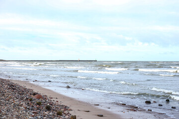 Coastal shore view with baltic sea and rocks on sand.