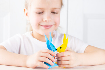 Beautiful smiling girl is playing with paper rabbits.