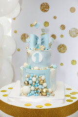 a light blue birthday cake decorated with a bow, hearts, crowns and balloons