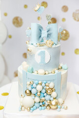 a light blue birthday cake decorated with a bow, hearts, crowns and balloons