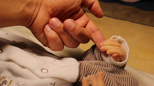 Newborn baby's hand trying to hold his dad 's hand, as symbol of family love and trust.
Moments of parents with their children.
Family healthcare and medical body part father's day concept.
New born