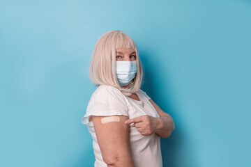 Elderly Vaccination. Healthy mature older senior 50s woman showing arm with plaster after vaccine,...