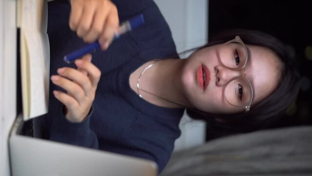 A cute Vietnamese girl is working on her computer and showing her cute facial expressions and  cute movements and saying something in front the camera