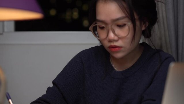 A Vietnamese girl is working on her computer as the camera is paning to her phone placed on the desk