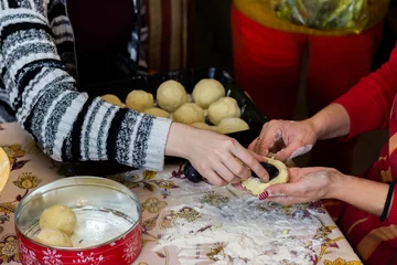 Foto op Canvas A mother teaching her daughter how to make plum dumplings. They are using internet recipe. © Jelena