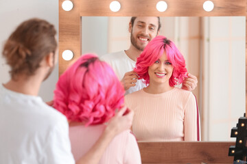 Obraz na płótnie Canvas Male stylist doing hair of young woman in beauty salon