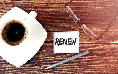 RENEW text on the sticky with coffee,pen and glasses on the wooden background
