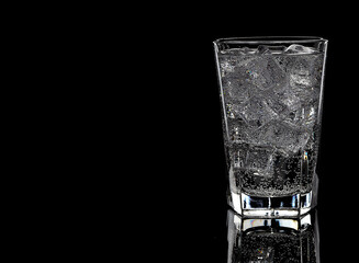 Glass with water and ice on black background, copy space