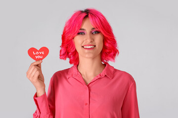 Stylish woman with bright hair and red heart on light background. Valentine's Day celebration