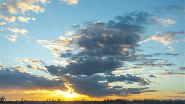 Beautiful sunset sky 4k stock video time lapse. Clear sunny blue sky and colorful white, yellow, purple clouds moving overhead isolated on blue sky background. Horizon line and gold sun shining