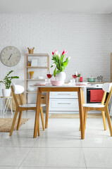 Dining table with stylish setting for International Women's Day celebration in kitchen