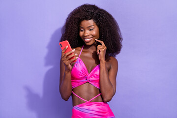 Photo of tricky cunning african lady dressed pink sexy clothes smiling typing modern device isolated violet color background