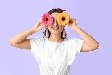 Young woman closing eyes with gerbera flowers on violet background. International Women's Day