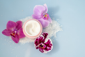 face and body cream with orchid flowers, body care concept, flat lay