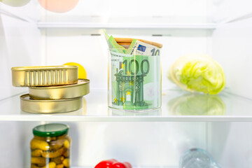 Money, cash euro banknotes in the refrigerator next to food. Concept of saving cash, shadow...