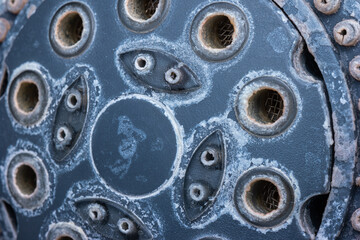 Silver metal shower head with hard water damage or lime scale calcium deposits. Close up studio macro shot, isolated on blue background