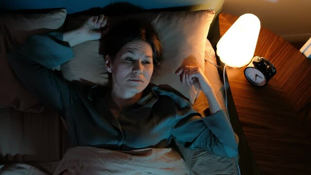 Depressed sad frustrated woman cannot sleep from insomnia, suffering from insomnia lying in bed.