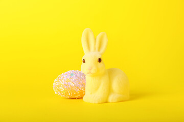 Beautiful Easter bunny and painted egg on yellow background