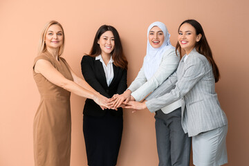 Beautiful women putting hands together on color  background. Unity concept