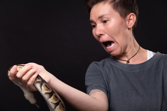 Photo of scared woman with python on black background