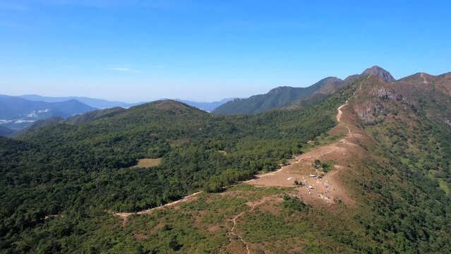 Beautiful dry bare plain for paragliding at the Ngong Ping with a winding gravel road to the top in Ma On Shan Hong Kong on a clear blue sunny summer day. Drone panning shot