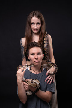 Photo of two women with snakes on black background