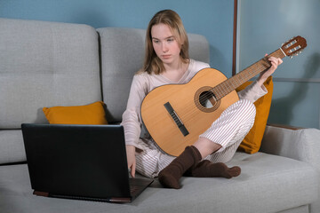 teenager girl plays the guitar at home. Hobby, distance learning, work. Music, mental health, relaxation, meditation