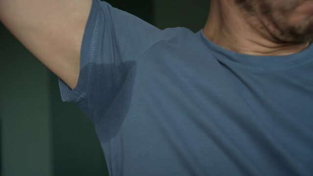Man in blue t-shirt with sweat stain on armpit, Hyperhidrosis sweating problem