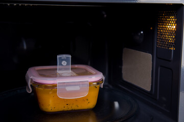 The storage container is in the microwave oven. There is soup in it.