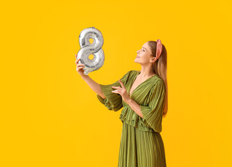 Beautiful woman with balloon in shape of figure 8 on yellow background. International Women's Day