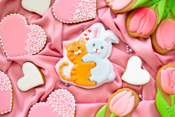 background banner greeting card for international women day or valentines day with cat and rabbit hugs, tulips and pigeon shape gingerbread cookies on pink silk fabric background