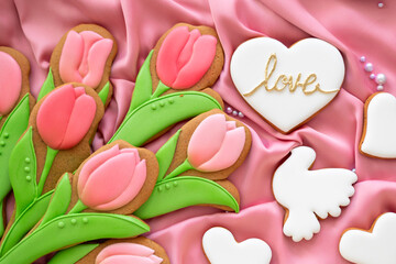 background banner greeting card for international women day or valentines day with white heart love, tulips and pigeon shape gingerbread cookies on silk fabric background