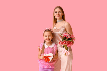 Little girl, her mother with tulips and gift on pink background