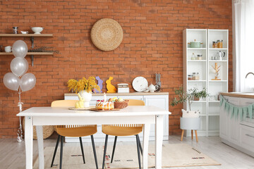 Easter cake, basket with eggs and mimosa flowers on dining table in kitchen interior