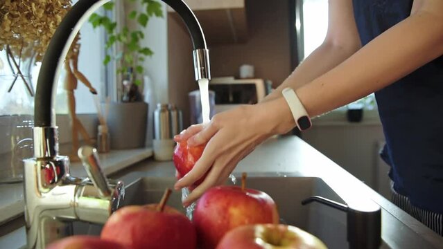 Caucasian woman washing red apples in kitchen sink at morning, Fruit diet and healthy nutrition